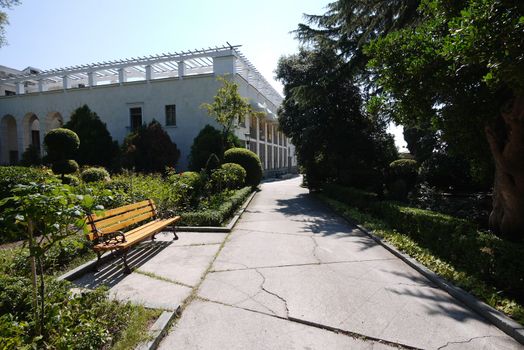 The sidewalk past the building and the bench on the roadside