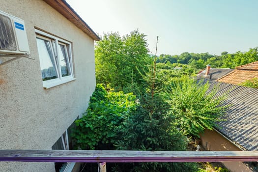 View from the balcony to the courtyard at the tall green trees and the nearest buildings of the building