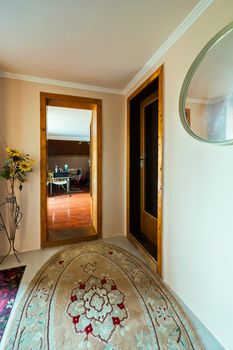 A beautiful oval-shaped carpet lying in the room near the wooden doors leading into the next room.