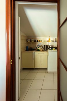 entrance through the wooden door to the room with bedside tables and cooking utensils