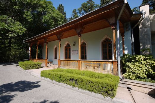 A beautiful veranda with a wooden roof and pillars against the background of the green park zone