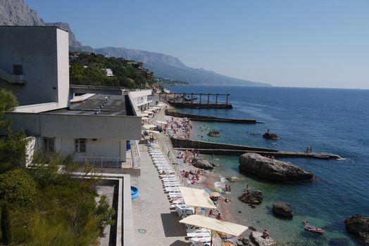 A resort complex with a large beach with white sun beds and umbrellas on the Black Sea coast