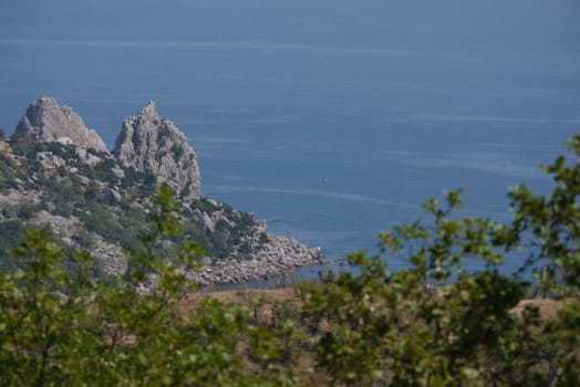 The only ship floating along the blue sea waves near the rocky mountains