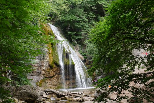 A beautiful waterfall with clear water flowing with stones in the forest