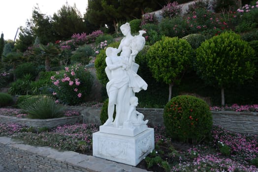 white garden sculpture on the background of beautiful plants