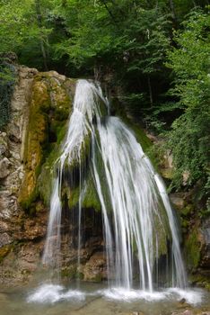 Beautiful scenic big waterfall against the backdrop of stone rock and green plantations