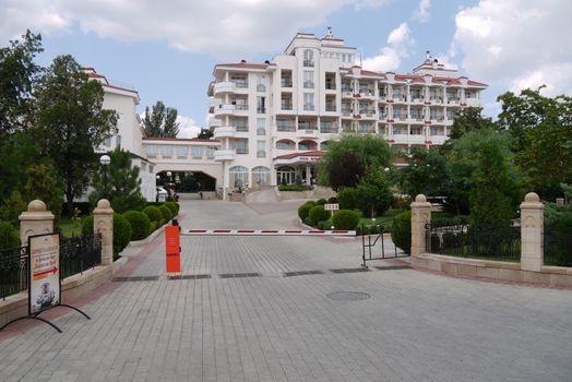 A paved road leads to a representative hotel with a barrier blocking the gates