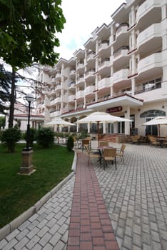 Tables with umbrellas for holidaymakers right under a large white building