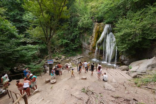 A group of tourists near a small waterfall. And around it is fresh, moist air