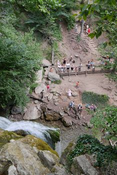 Tourists watch the waterfall from an observation deck located on a descent from a cliff