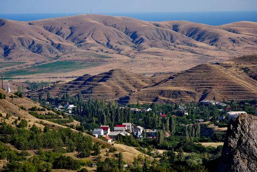 Houses in the countryside among the trees next to the low mountains are rugged roads and similar to the Egyptian pyramids.