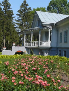 A dense, beautiful flowerbed with pink flowers at the front of the house of white color