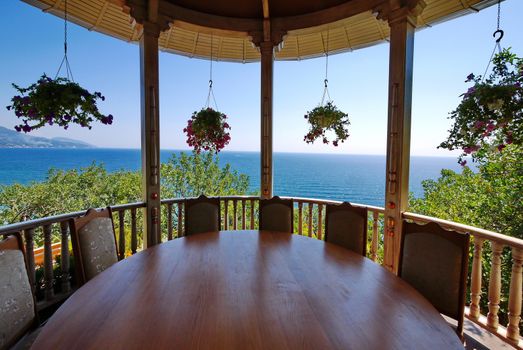 dining table in a gazebo with flowers on the background of the sea