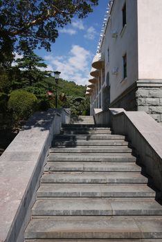 A ladder with granite steps going up along the building and mountain slopes in the distance