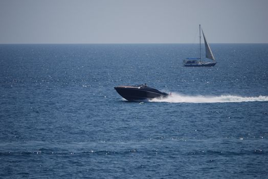 Boat and sailing yacht compete who is faster in the blue sea