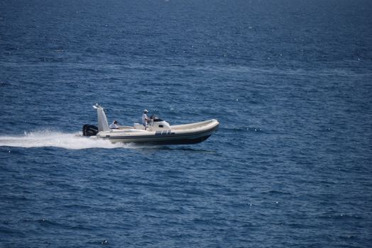 The inflatable motor boat breaks blue sea waves on a sunny day