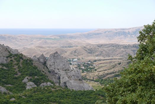 houses lying in the valley between the rocky mountains and the sea in the distance