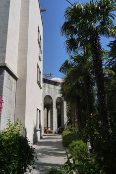 alley to the arches near the white front of the house with an exotic park