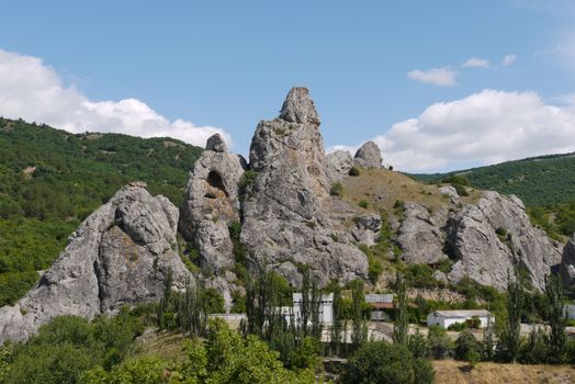 Gray rocks with caves above houses. It looks pretty dangerous