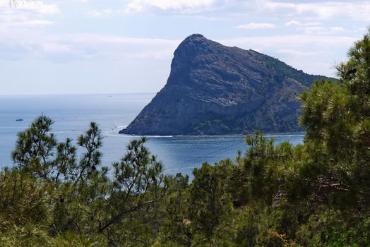 A picturesque view of a rocky sheer mountain against the backdrop of the endless blue sky