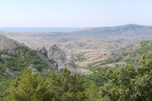 a panorama of uncultivated hills with a settlement in the valley against the background of the endless sea