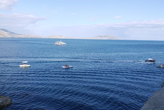 a large liner and small boats rock on the blue sea waves near the bay