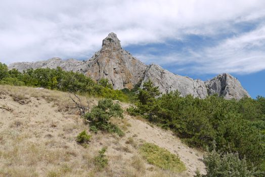 The gray rock is triangular in shape against the blue sky with white divorces