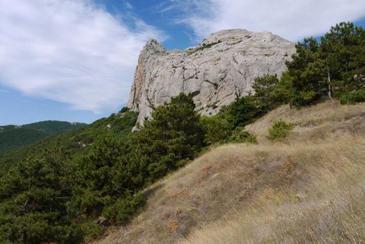 a mountain cliff on a green slope propped up by its apex with a vault of heaven