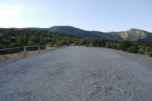 view of the Crimean mountains from a country road with a wooden fence