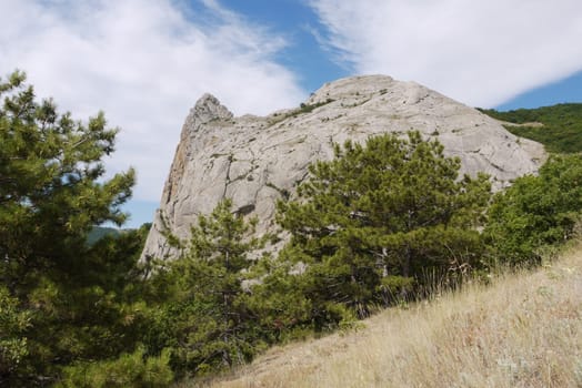 blue sky with clouds lying on a small mountain cliff