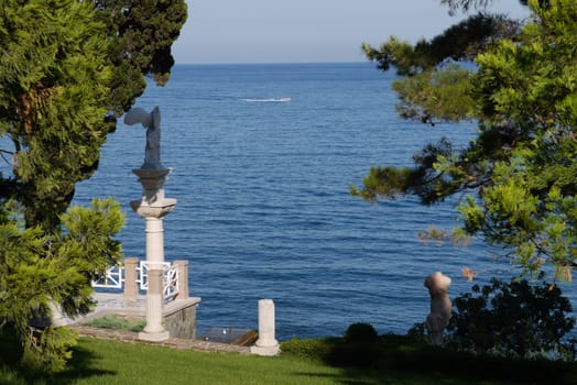 view from the park on a lone boat cutting blue and endless sea-level