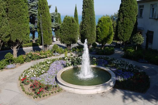 neat round-shaped fountain among the flower beds with beautiful flowers