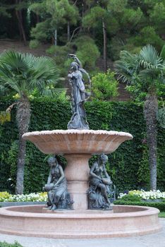 Fountain in the form of a cup and sculpture of three girls with vases of water near it