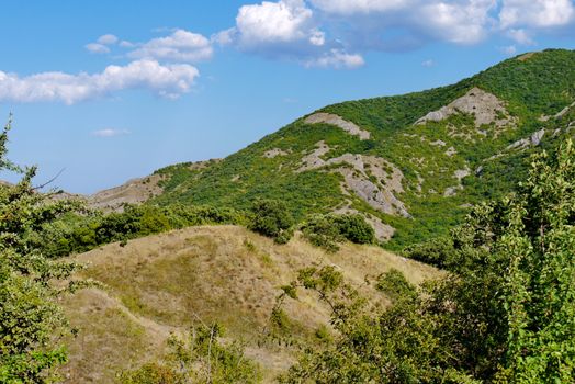 high steep grass-covered slope on the blue sky background