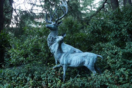Decorative sculpture depicting two forest animals against a background of green bushes and trees