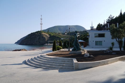 A small park with a sculpture of Neptune on the rocks and a beautiful view of the sea and mountains