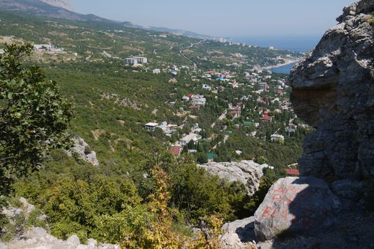 a small cozy coastal town on the background of the high mountains covered with trees