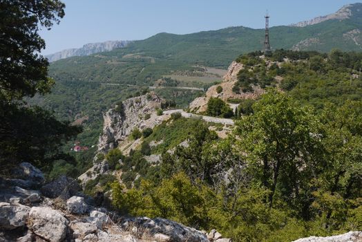 twisted rocky road against the background of high mountains covered with trees