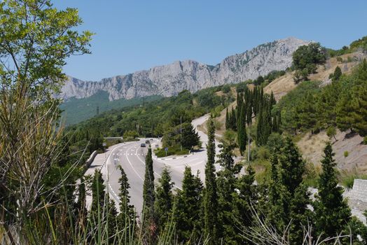 the road is twisted on the background of the steep cliffs surrounded by dense forest