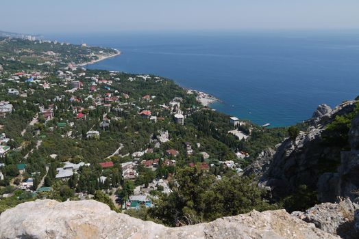 a small rock on the background of a beautiful quiet coastal town under a blue sky