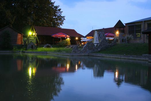 a small lake under the evening sky on the background of a cozy cafe