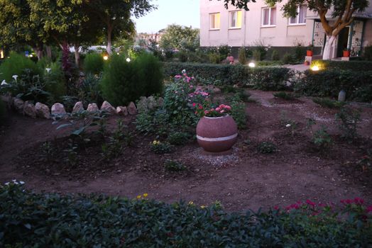 large flowered flower bed with night lights on the background of the house