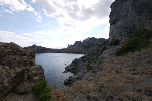 The wide bay is surrounded by high Crimean rocks covered with grass