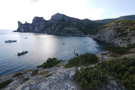 small boats in the middle of a wide bay of the black sea surrounded by high slopes