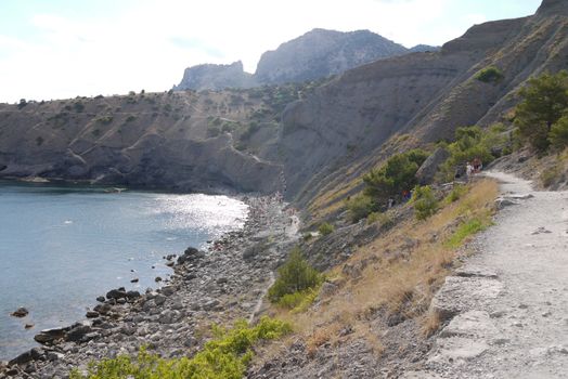 a long narrow road under high Crimean rocks against a blue sky background.Walking in the nature