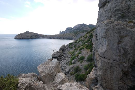 The wide bay is surrounded by high Crimean rocks covered with grass