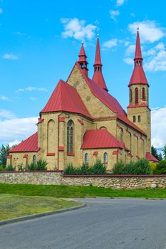 Beautiful brick building with a red roof in a Gothic style on the blue sky background