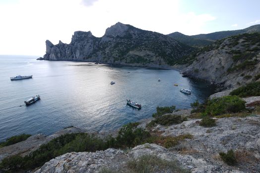 small boats in the middle of a wide bay of the black sea surrounded by high slopes