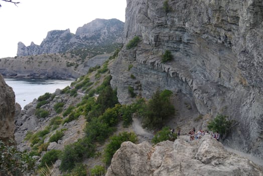 a long narrow road under high Crimean rocks against a blue sky background.Walking in the nature