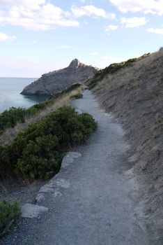 a small path on the background of rocks and boundless black sea